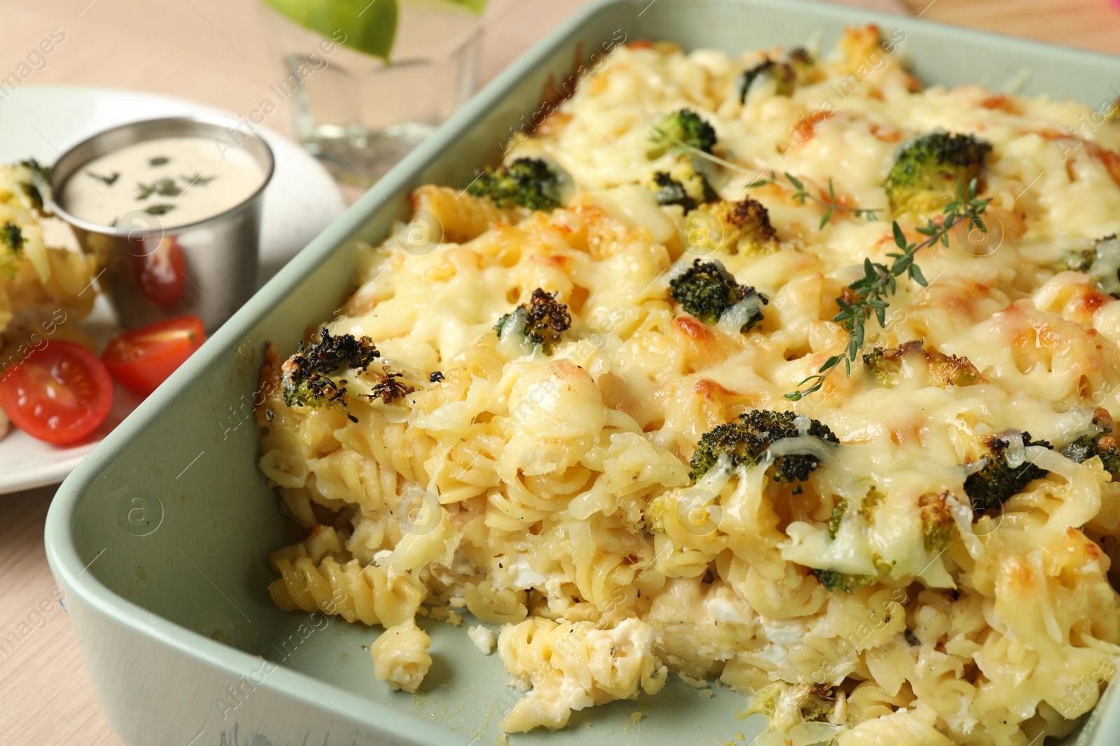 Photo of Tasty pasta casserole with cheese and broccoli in baking dish on wooden table, closeup