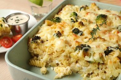 Photo of Tasty pasta casserole with cheese and broccoli in baking dish on wooden table, closeup