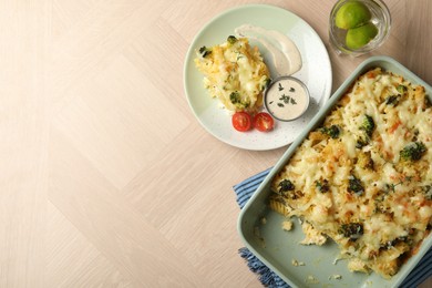 Photo of Tasty pasta casserole with cheese and broccoli served on wooden table, flat lay. Space for text