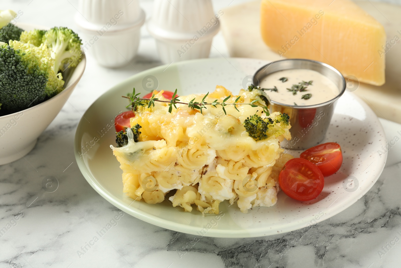 Photo of Tasty pasta casserole with cheese and broccoli served on white marble table, closeup