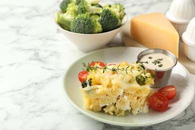 Photo of Tasty pasta casserole with cheese and broccoli served on white marble table, closeup. Space for text