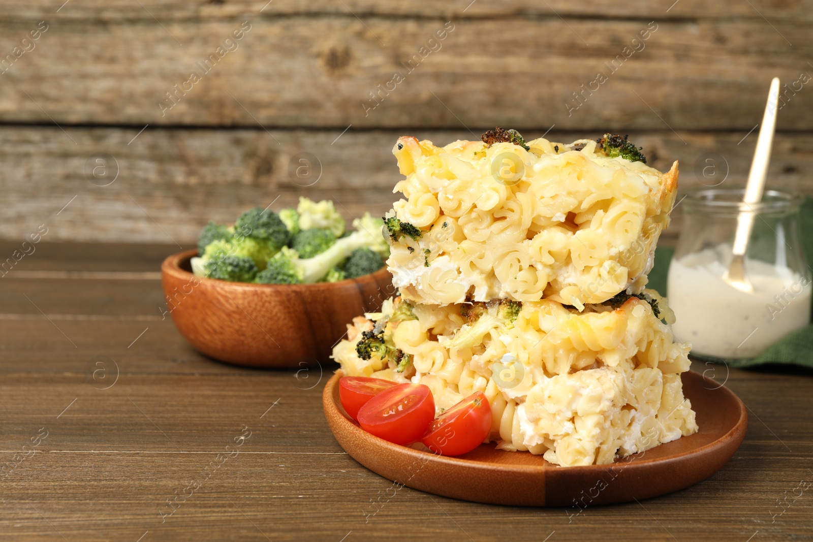 Photo of Tasty pasta casserole with cheese and broccoli served on wooden table