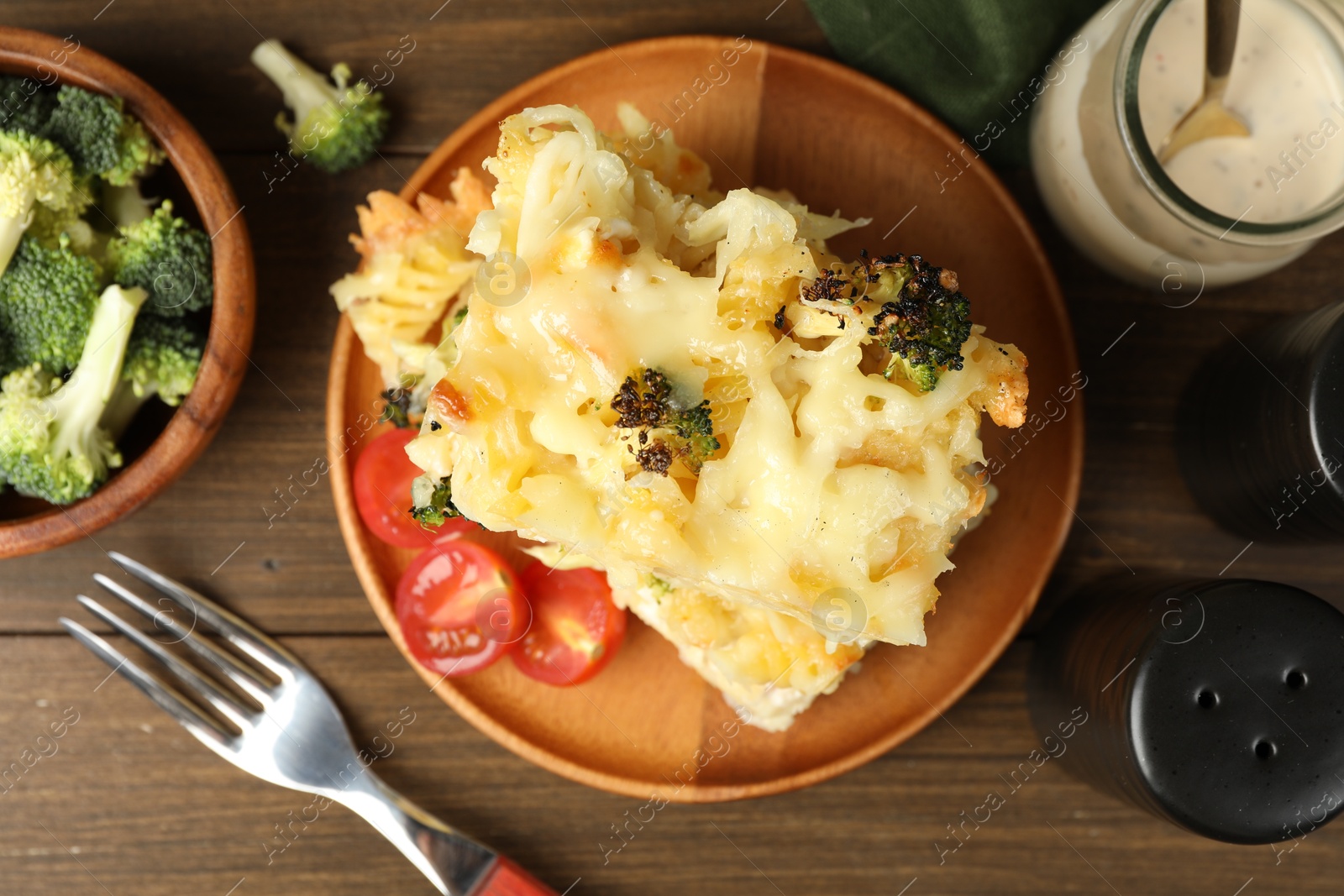 Photo of Tasty pasta casserole with cheese and broccoli served on wooden table, flat lay