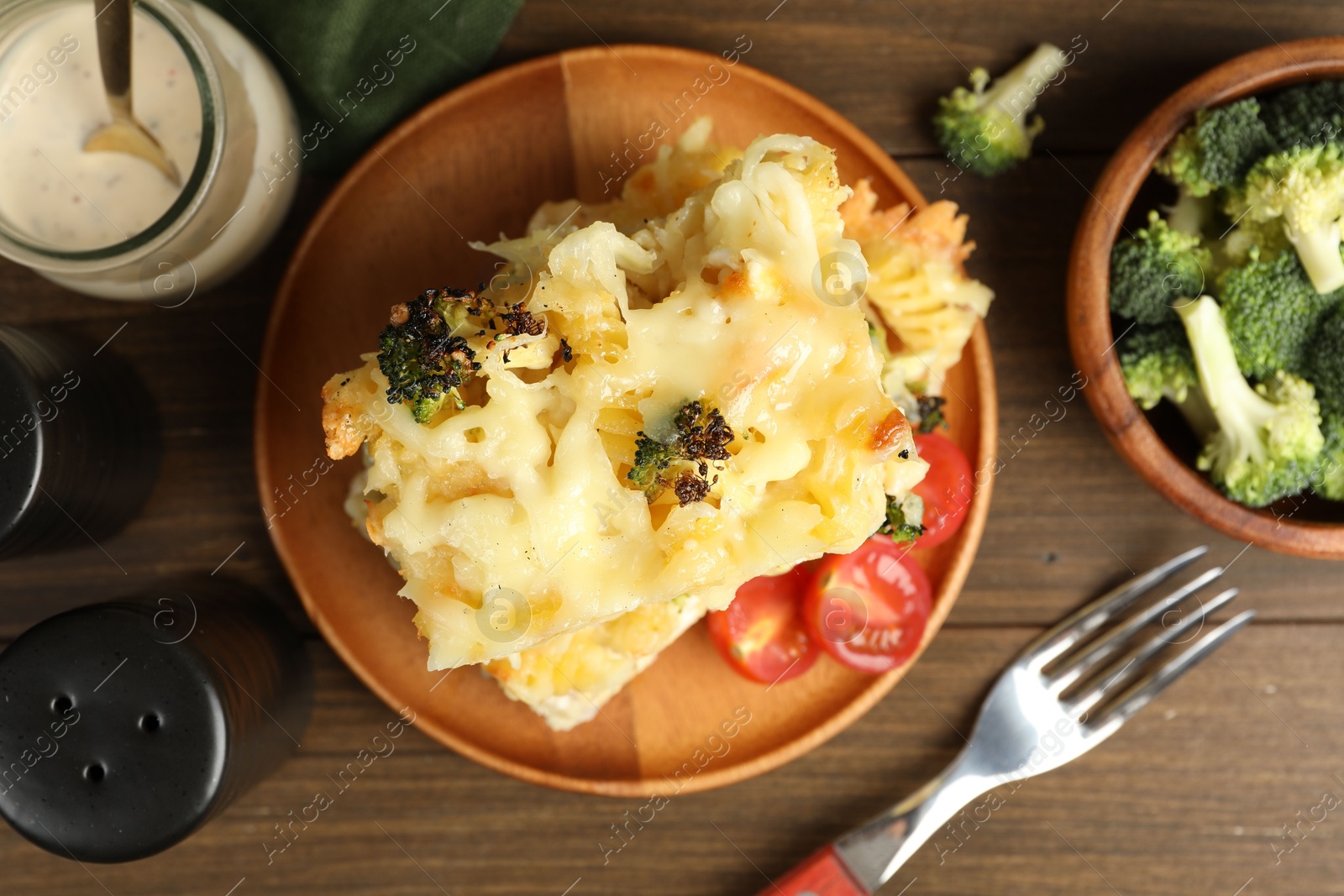 Photo of Tasty pasta casserole with cheese and broccoli served on wooden table, flat lay