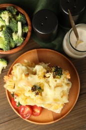 Photo of Tasty pasta casserole with cheese and broccoli served on wooden table, flat lay