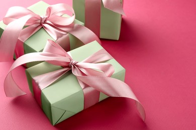 Photo of Beautiful gift boxes with bows on pink background, space for text