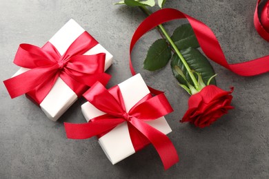 Photo of Gift boxes with bows and rose on grey table, flat lay