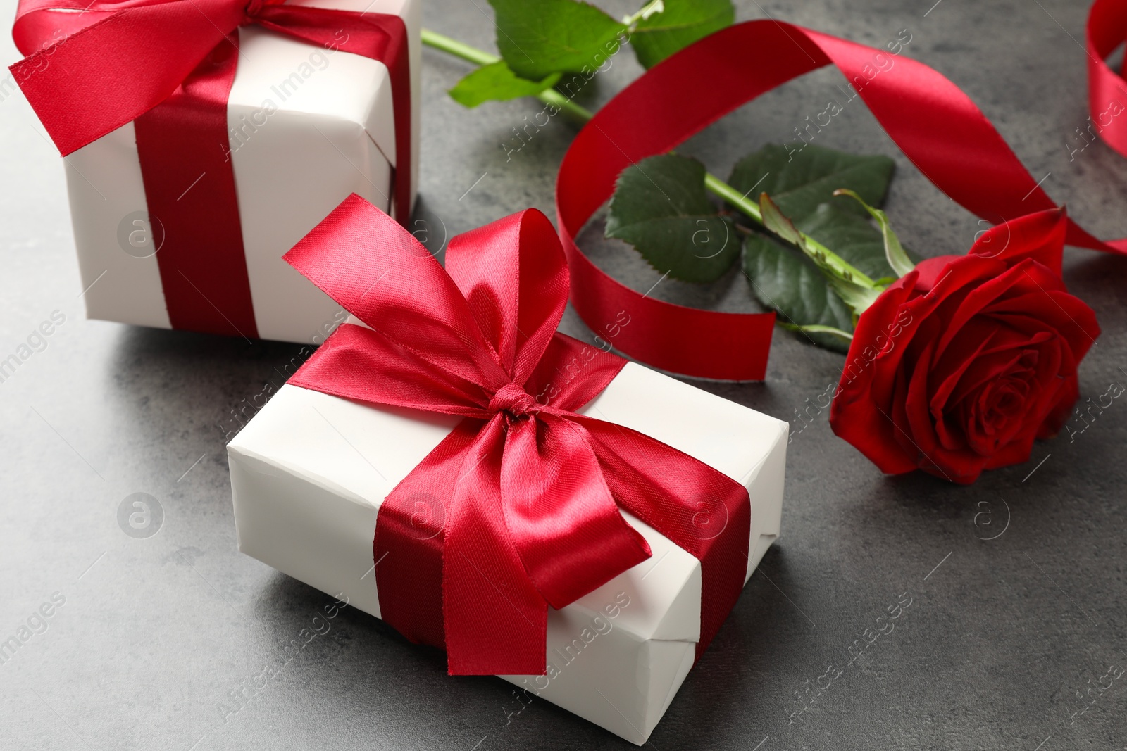 Photo of Gift boxes with bows and rose on grey table