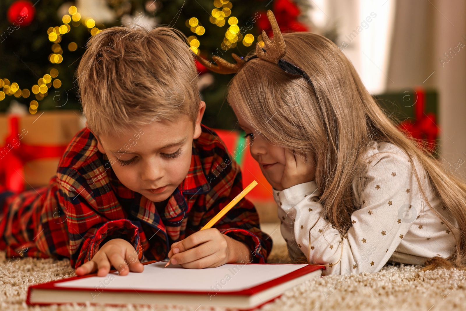 Photo of Little kids writing letter to Santa Claus on floor at home. Christmas celebration