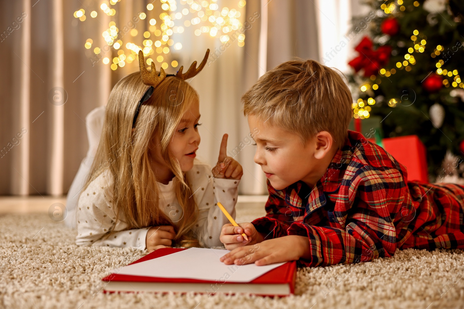 Photo of Little kids writing letter to Santa Claus on floor at home. Christmas celebration