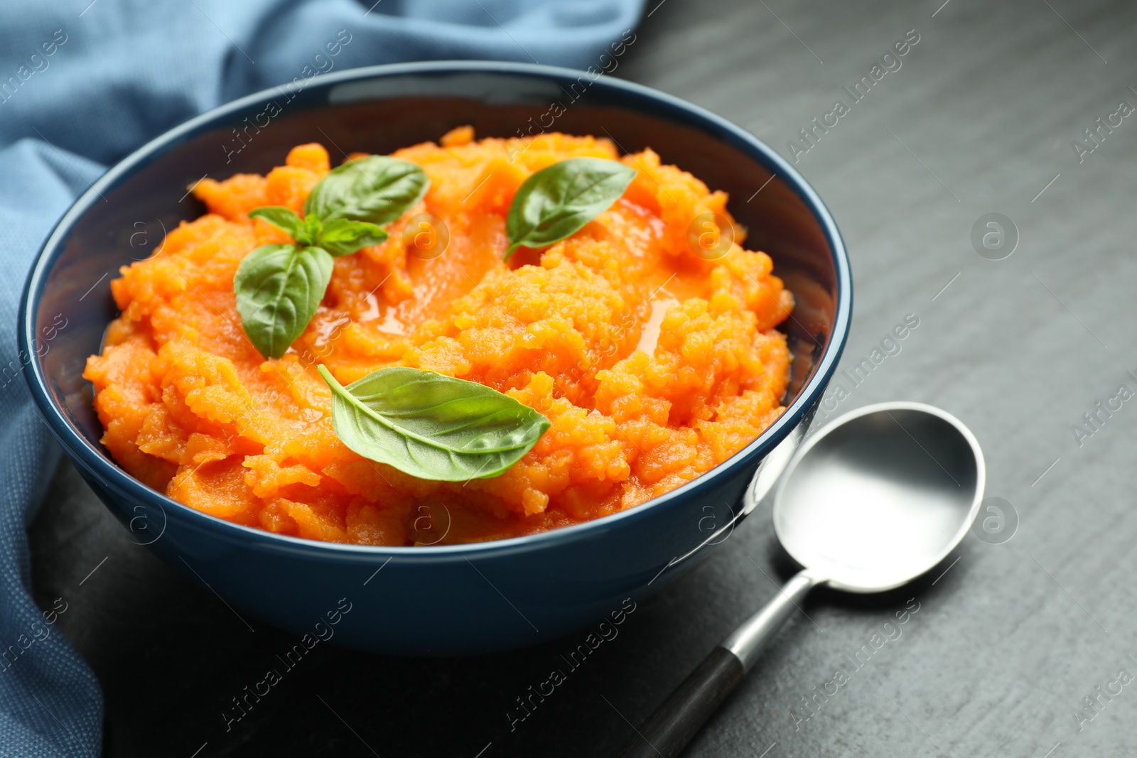 Tasty mashed sweet potato in bowl served on dark gray textured table, closeup Photo of Tasty mashed sweet potato in bowl served on dark gray textured table, closeup