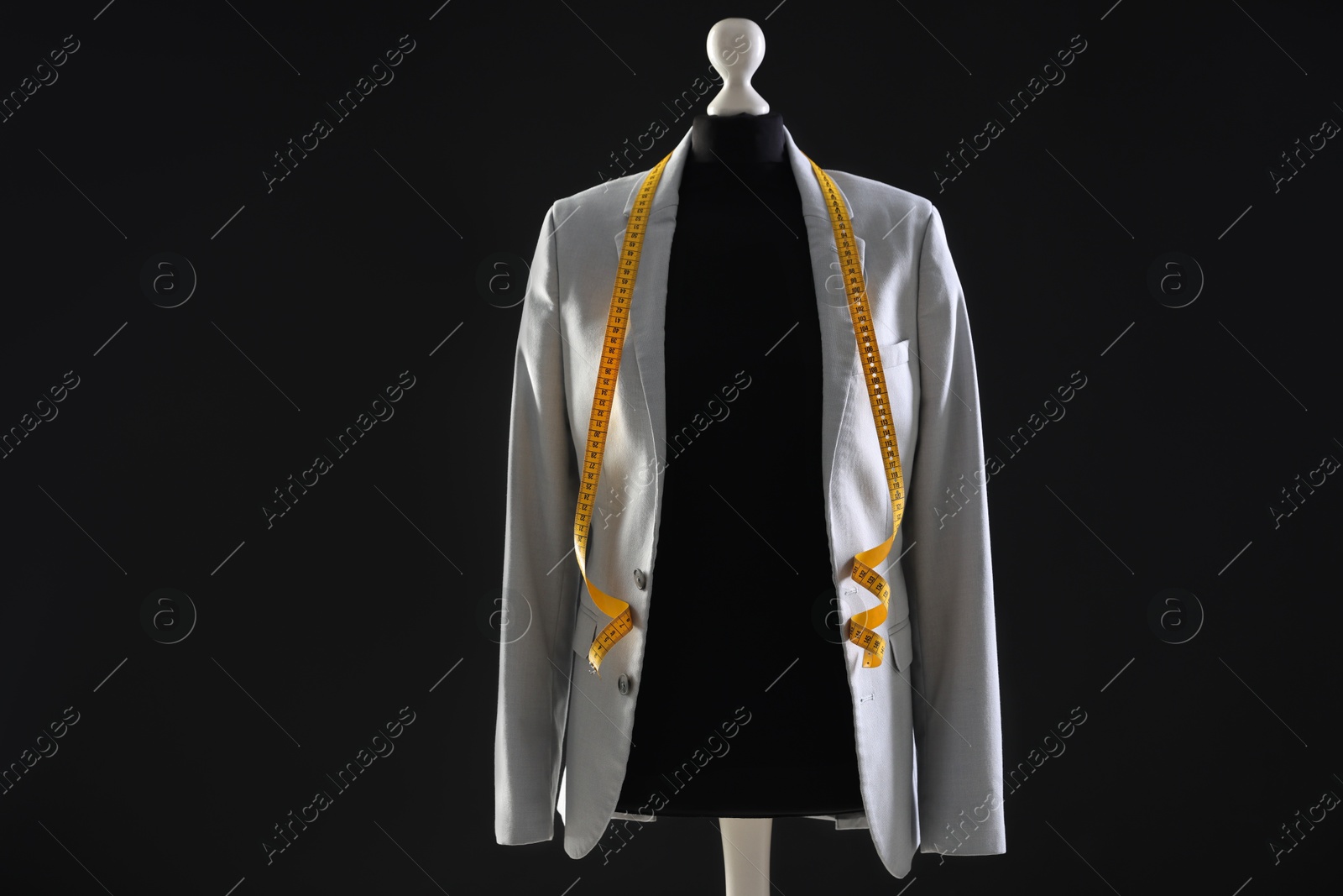 Photo of Female mannequin with gray jacket and measuring tape on dark background