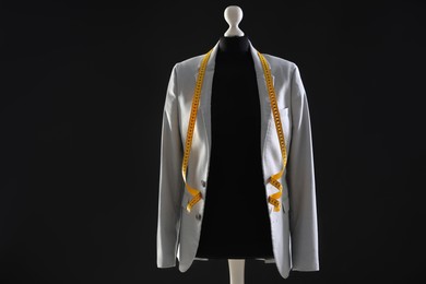 Photo of Female mannequin with gray jacket and measuring tape on dark background