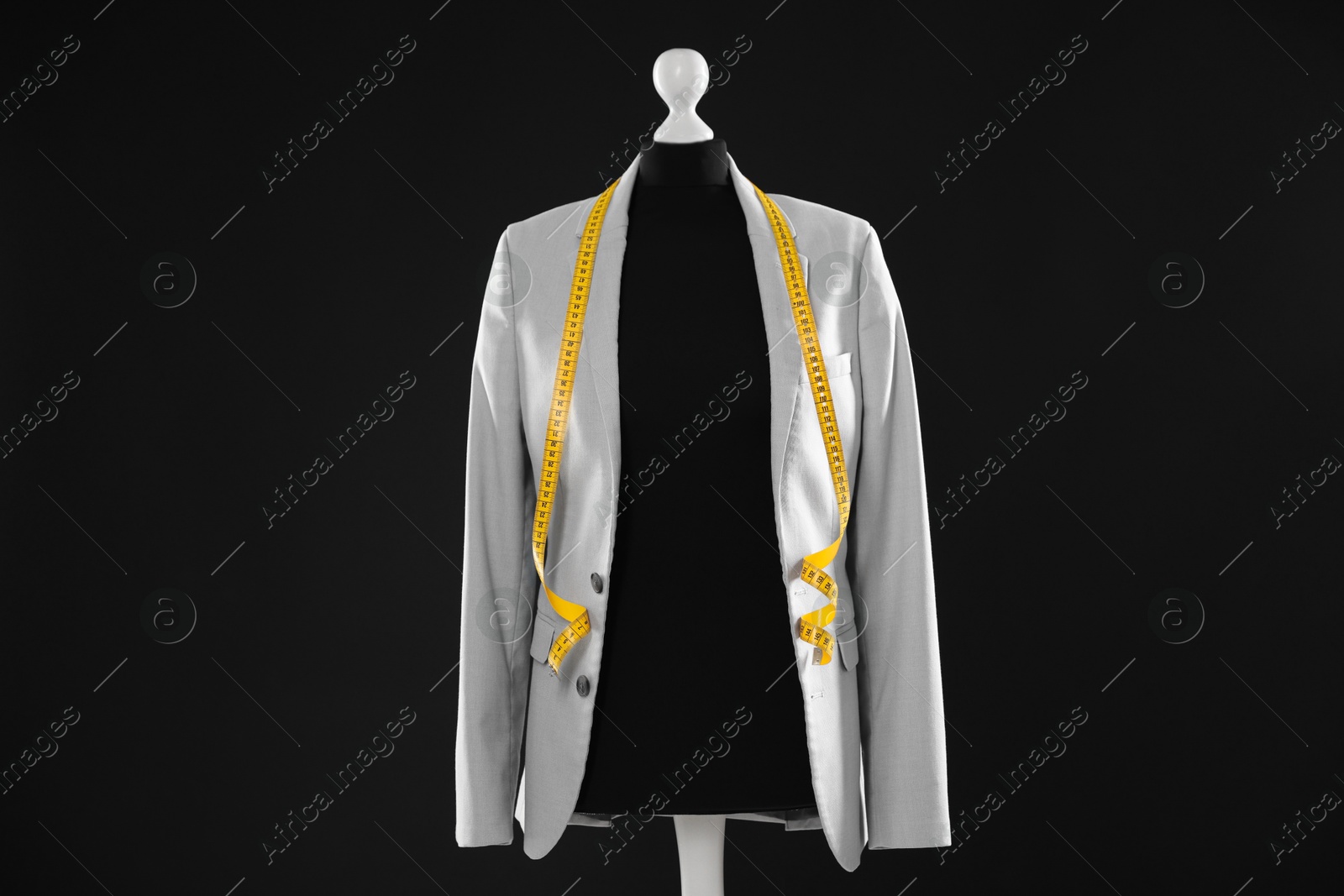 Photo of Female mannequin with gray jacket and measuring tape on dark background