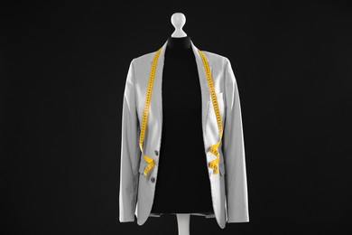 Photo of Female mannequin with gray jacket and measuring tape on dark background