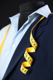 Photo of Male mannequin with jacket, shirt and measuring tape on black background, closeup