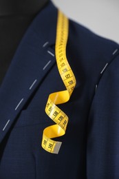 Photo of Semi-ready jacket and measuring tape on mannequin against gray background, closeup