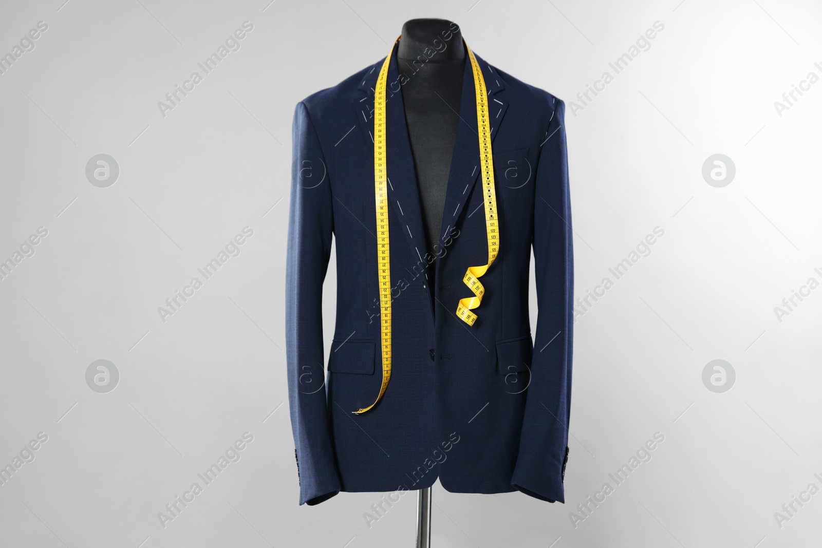 Photo of Semi-ready jacket and measuring tape on mannequin against gray background