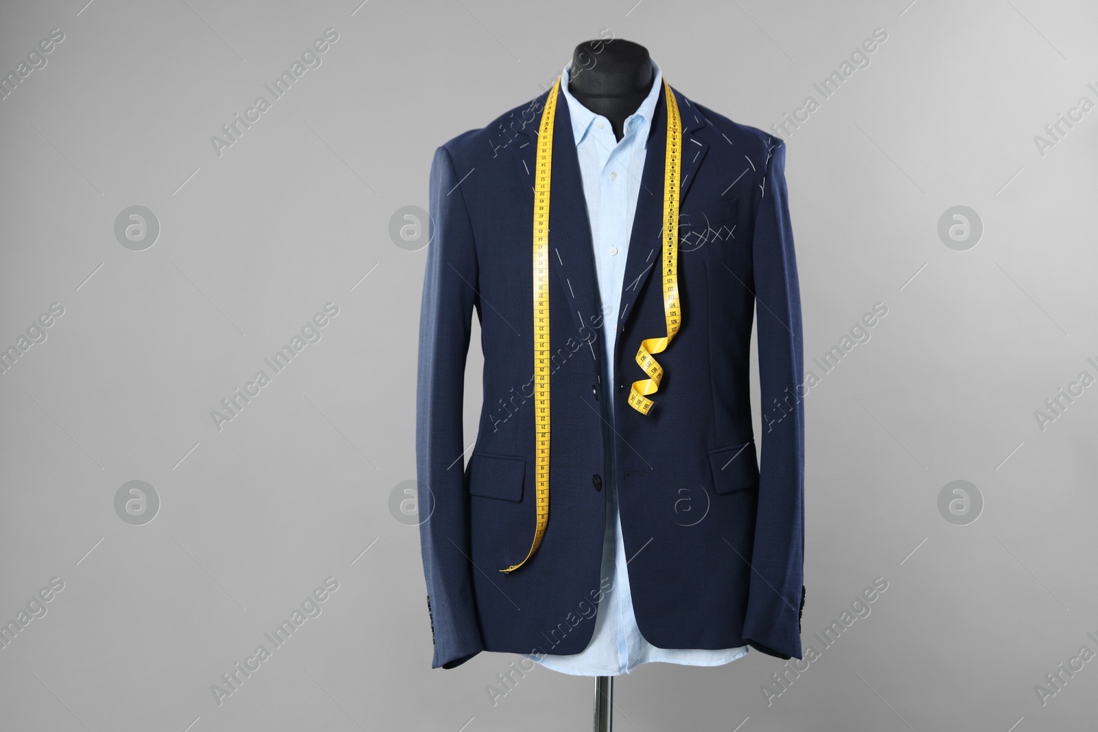 Photo of Semi-ready jacket, shirt and measuring tape on mannequin against gray background