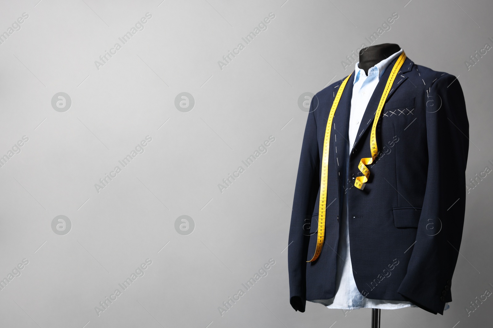 Photo of Semi-ready jacket, shirt and measuring tape on mannequin against gray background, space for text