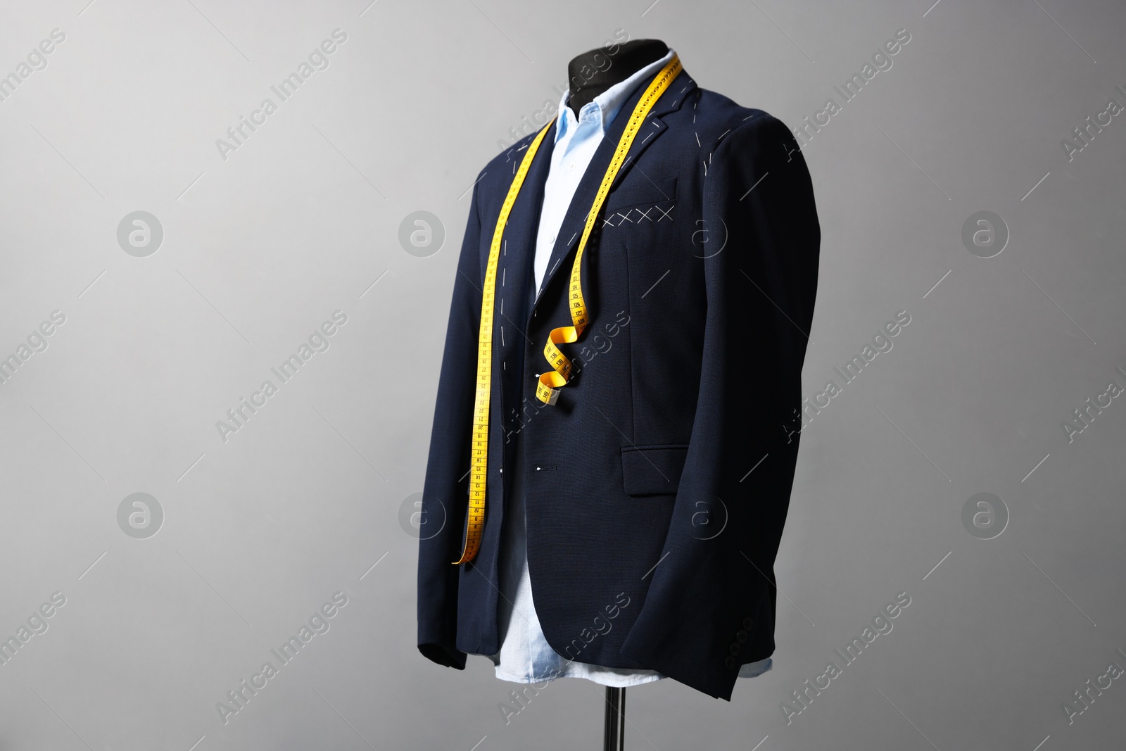 Photo of Semi-ready jacket, shirt and measuring tape on mannequin against gray background