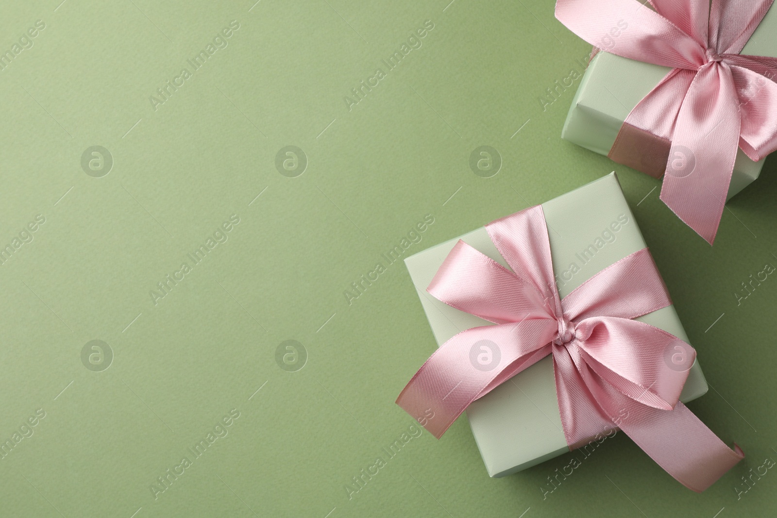 Photo of Gift boxes with pink bows on green background, top view. Space for text