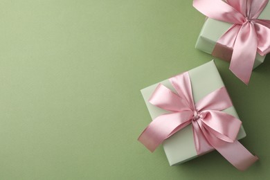 Photo of Gift boxes with pink bows on green background, top view. Space for text