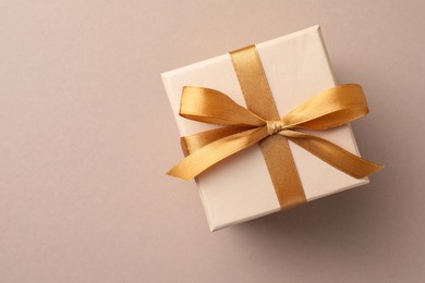 Photo of Gift box with golden bow on beige background, top view. Space for text