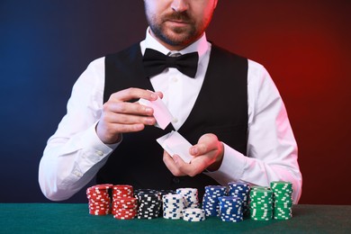 Photo of Professional croupier shuffling cards at gambling table, closeup