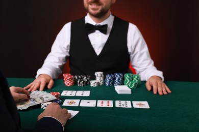 Photo of Gambler making bet with professional croupier at gambling table, closeup