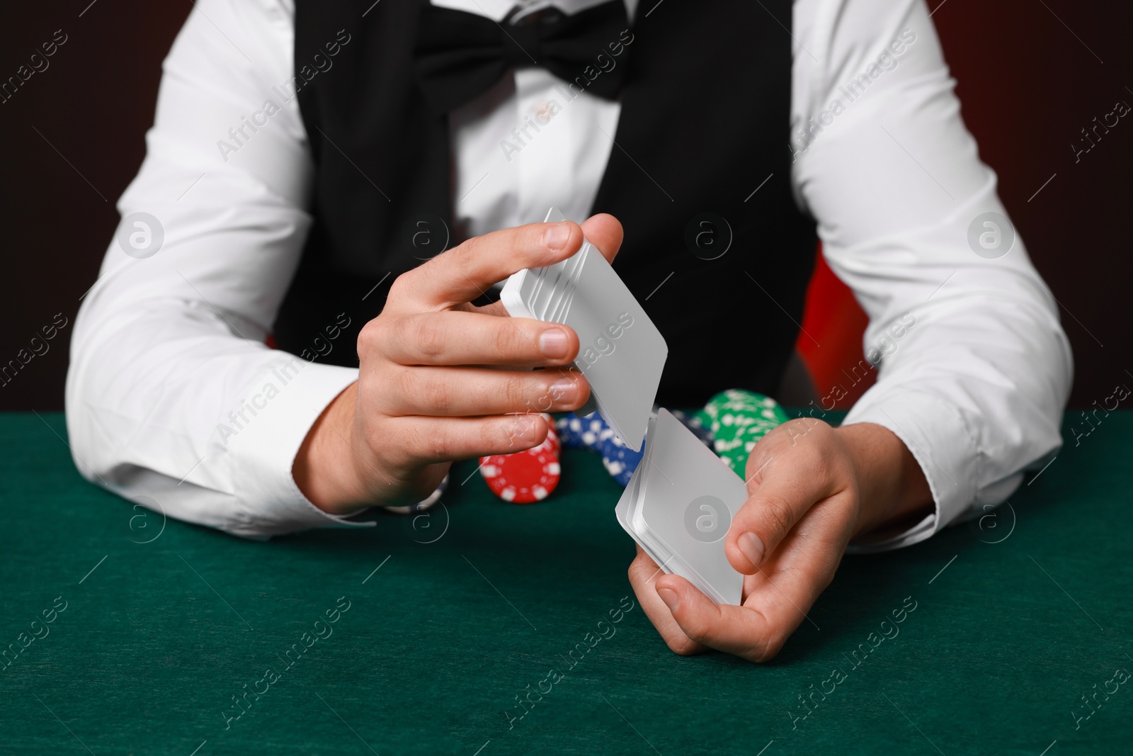 Photo of Professional croupier shuffling cards at gambling table, closeup