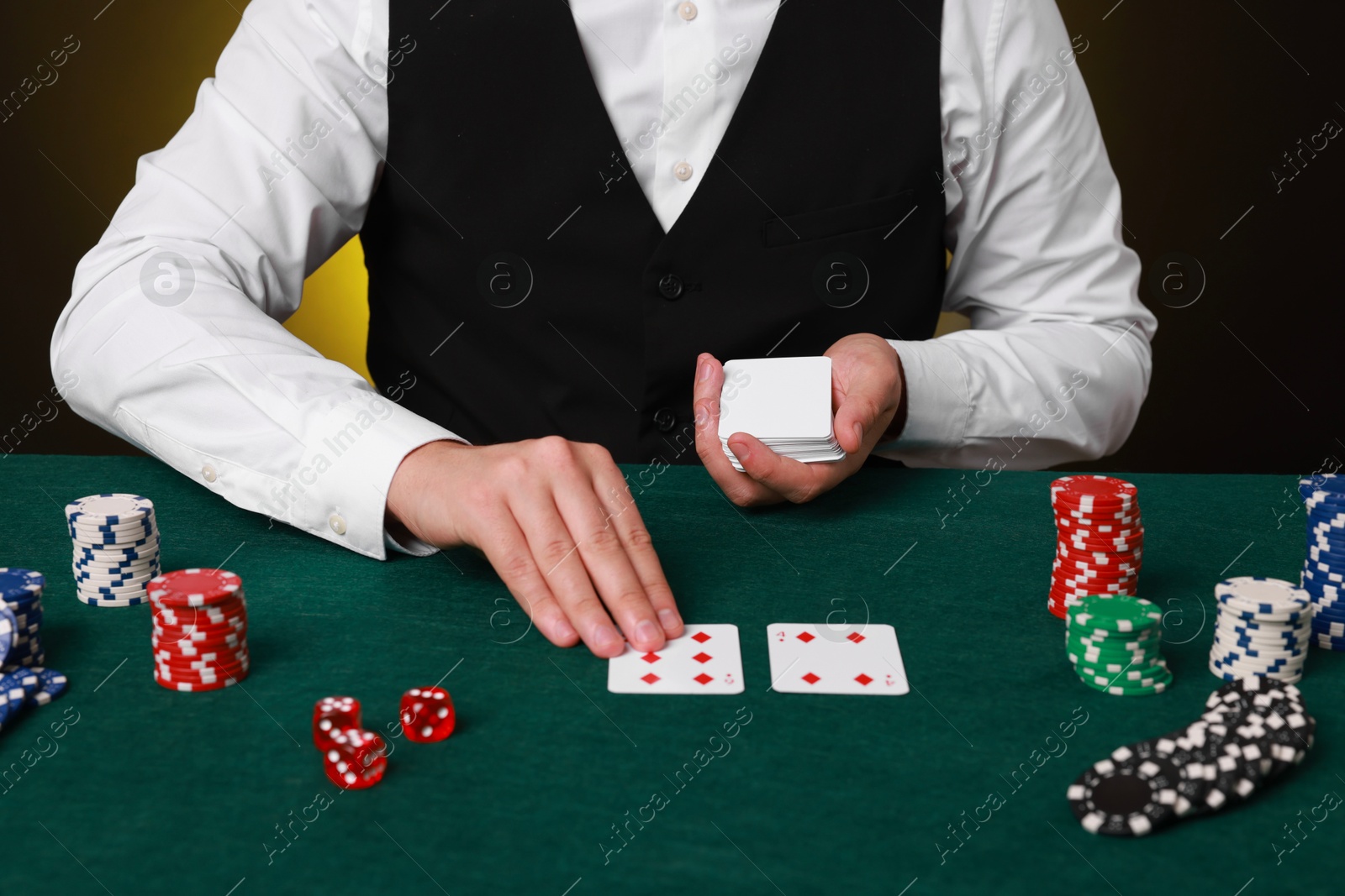 Photo of Professional croupier with playing cards at gambling table, closeup