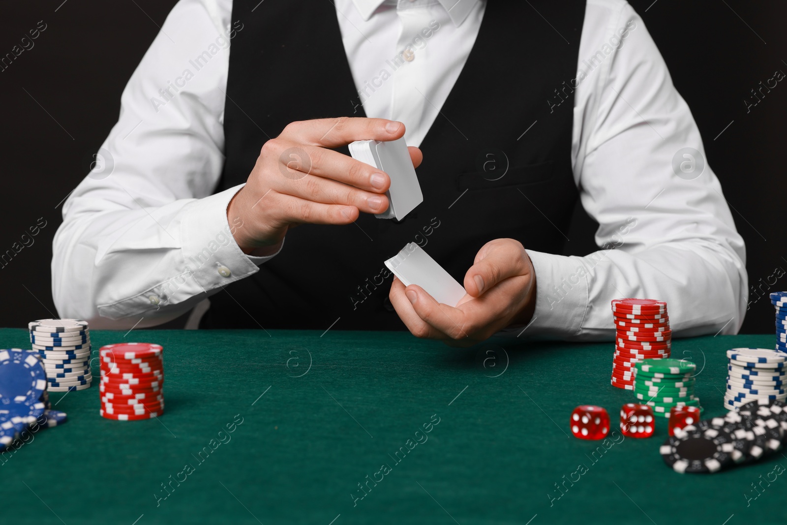 Photo of Professional croupier shuffling cards at gambling table, closeup