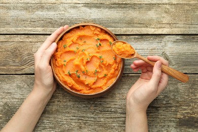 Photo of Woman eating tasty mashed sweet potato at wooden table, top view