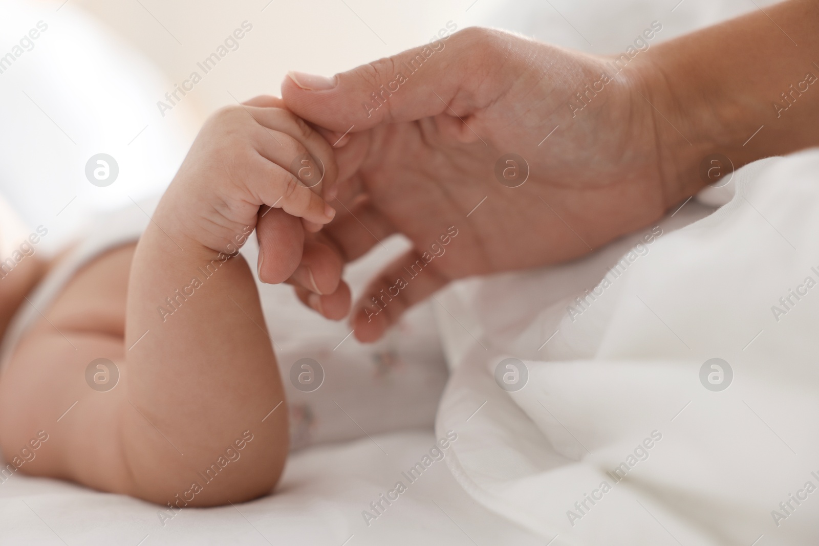 Photo of Mother with her sleeping little baby on bed at home, closeup