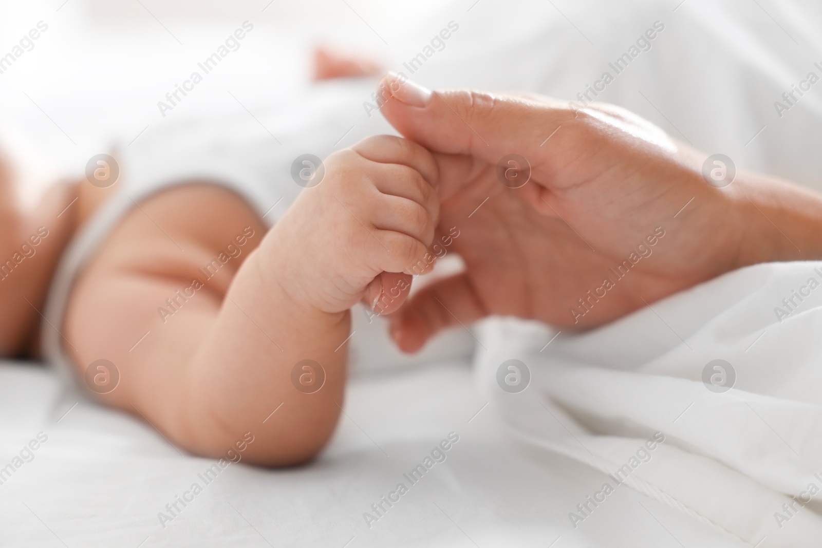 Photo of Mother with her sleeping little baby on bed at home, closeup