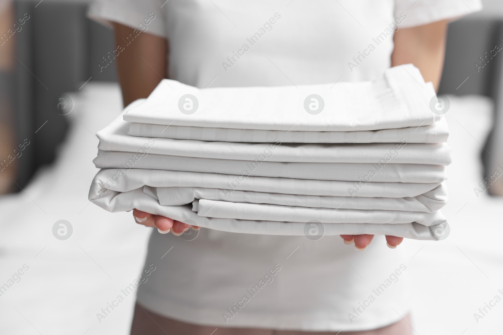 Photo of Woman with clean bed linens indoors, closeup