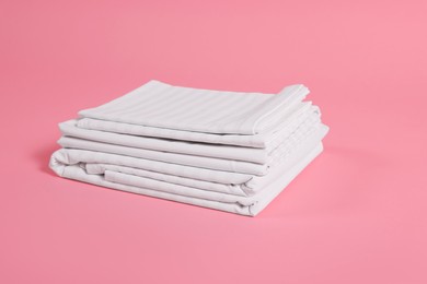 Photo of Stack of clean bed linens on pink background