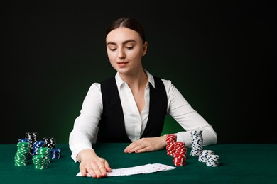 Photo of Professional croupier with casino chips and playing cards at gambling table on color background