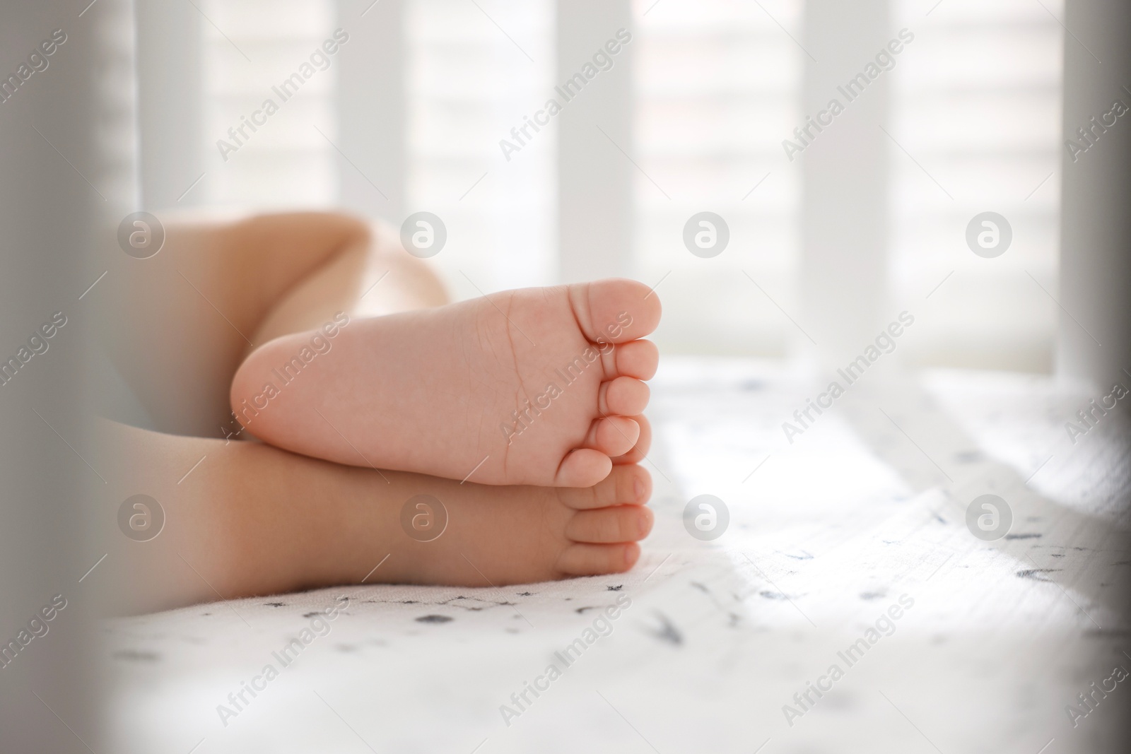 Photo of Little baby sleeping in crib indoors, closeup. Space for text