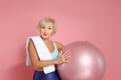 Photo of Senior woman with towel and fitness ball on pink background