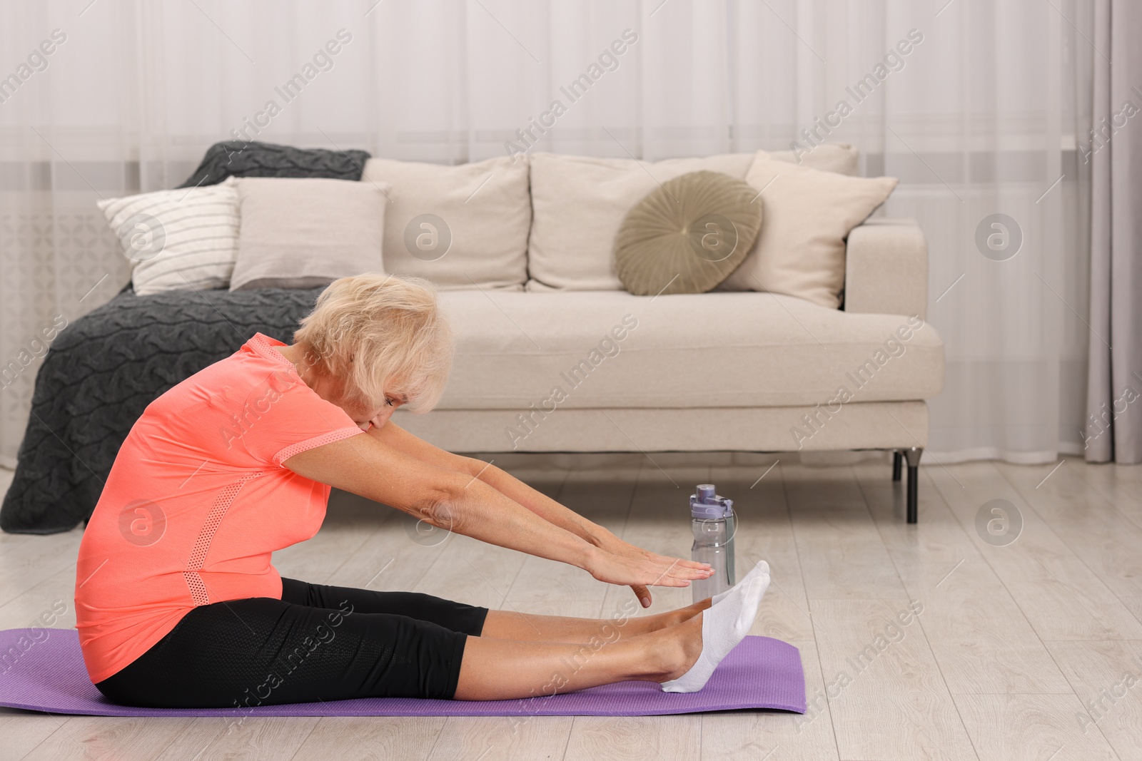 Photo of Senior woman exercising with fitness mat at home