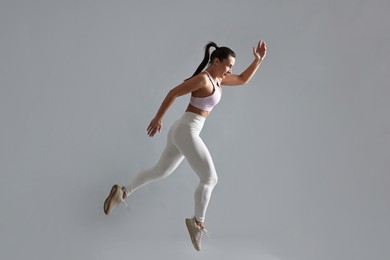 Photo of Woman in gym clothes doing exercise on grey background