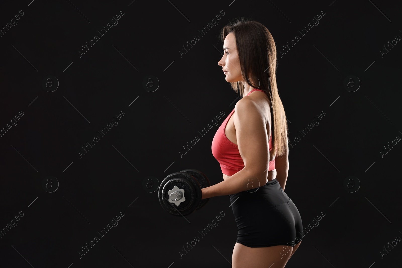 Photo of Woman in gym clothes exercising with barbell on black background