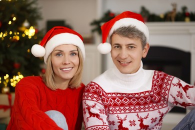 Lovely couple in Santa hats and Christmas sweaters at home