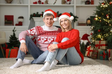 Lovely couple in Santa hats and Christmas sweaters at home