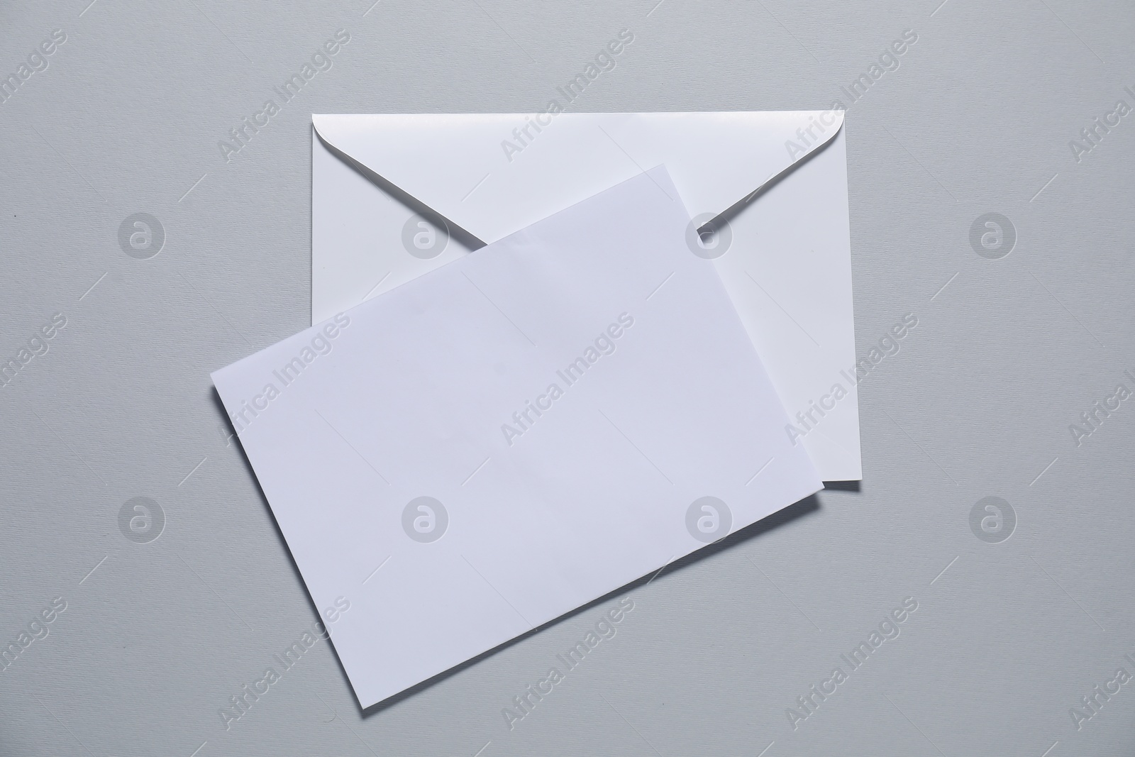 Photo of Paper envelope with letter on gray background, top view. Mockup for design