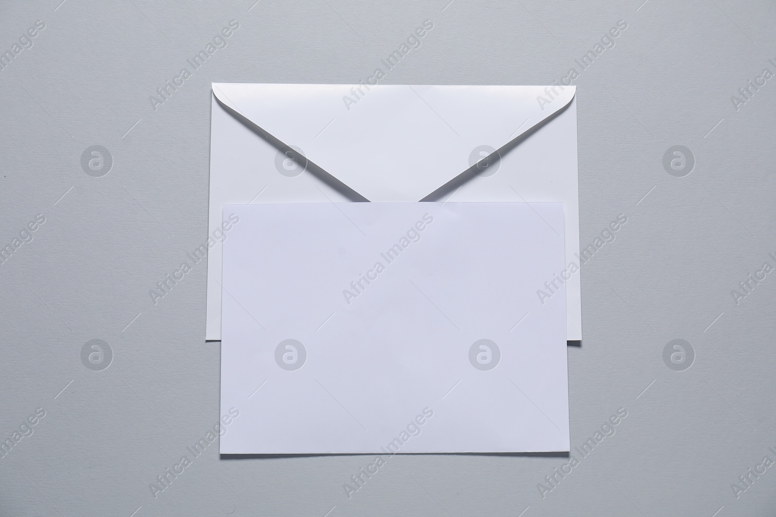 Photo of Paper envelope with letter on gray background, top view. Mockup for design