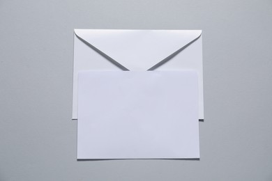 Photo of Paper envelope with letter on gray background, top view. Mockup for design