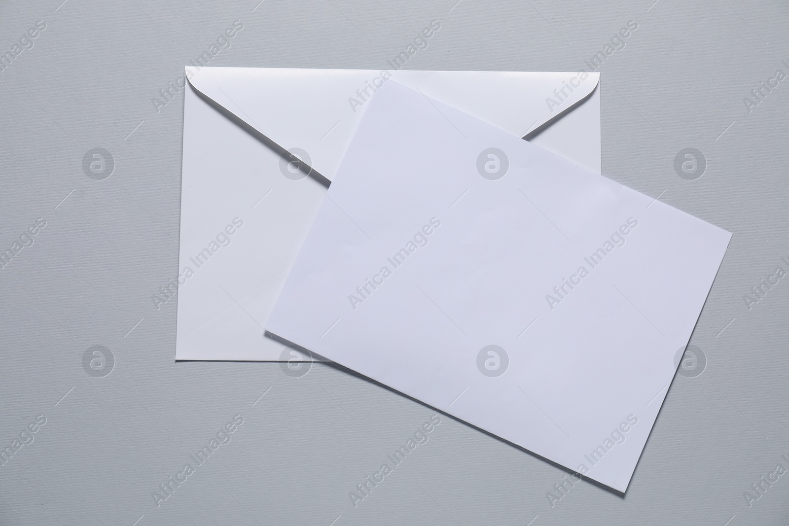 Photo of Paper envelope with letter on gray background, top view. Mockup for design